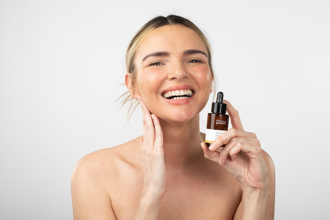 Frasco de vitamina C sobre fondo blanco junto a productos antimanchas